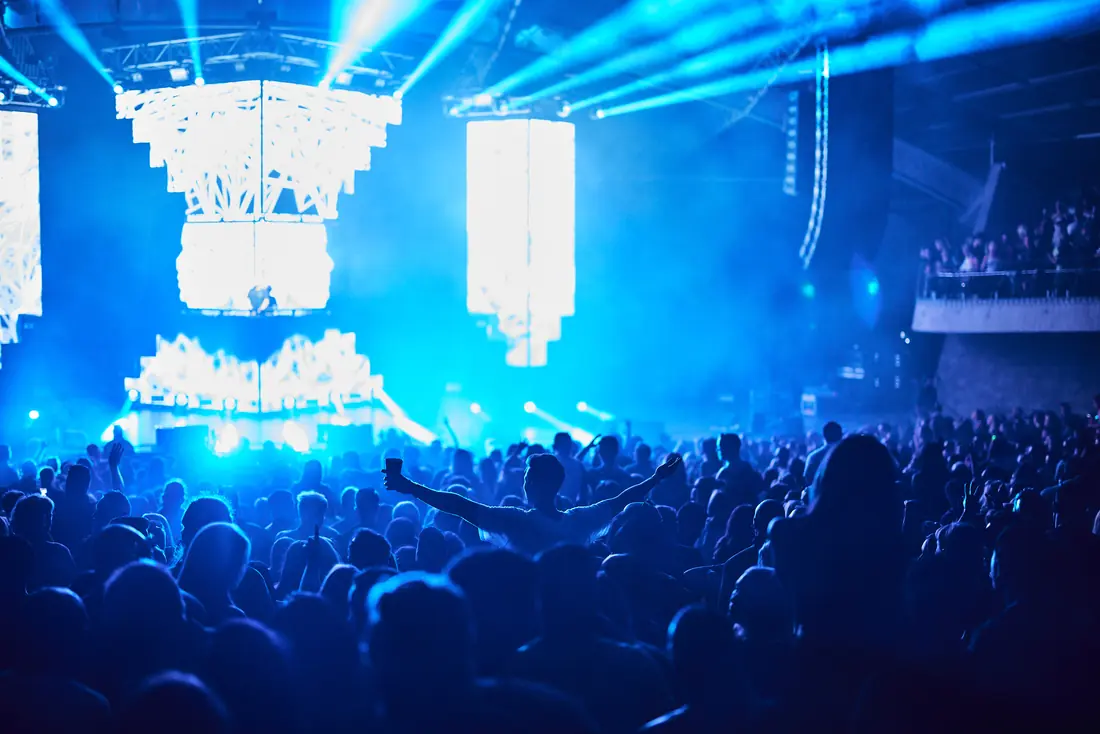 Crowd in silhouette against bright blue stage screens
